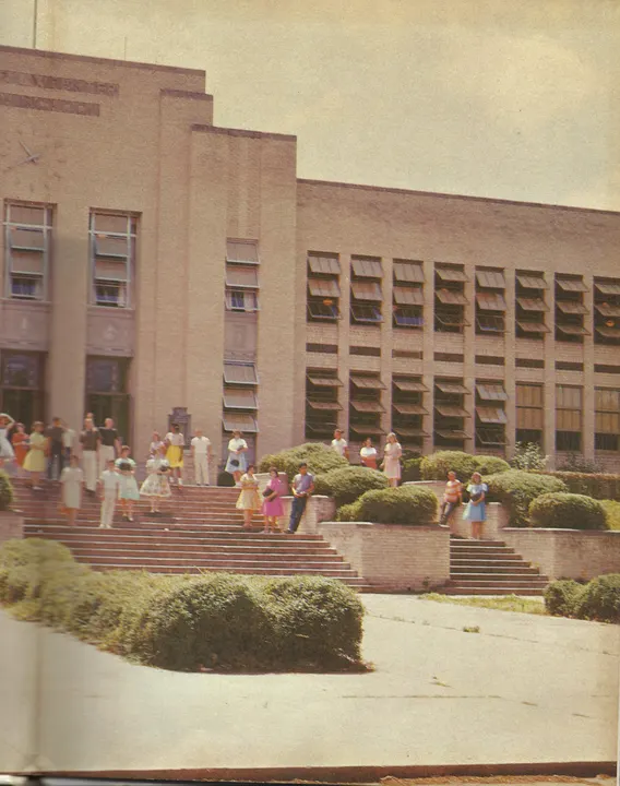 Students on the steps and lawn in front of Webster’s brick school building.