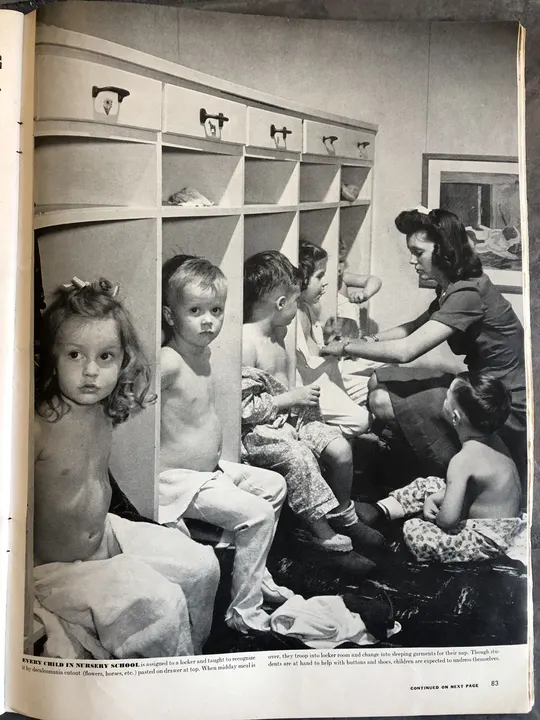 A historical magazine photograph of a student helping young children at classroom cubbies.