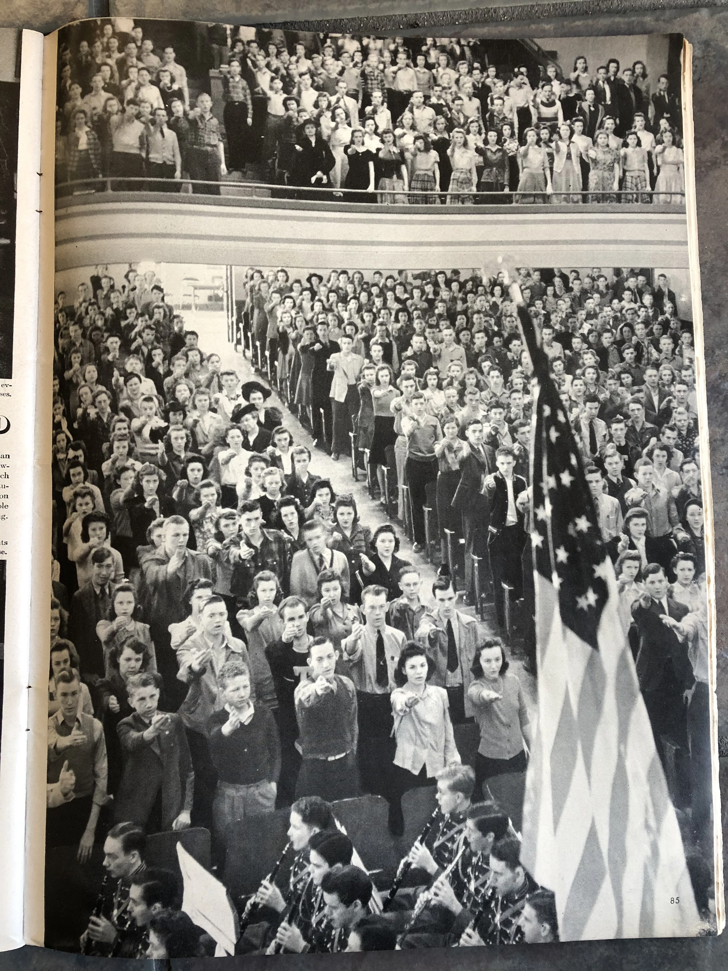 Students in a crowded school assembly taking part in a historical flag-pledge ceremony.